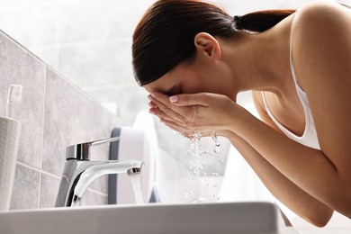 Photo of Woman washing her face over sink in bathroom, low angle view