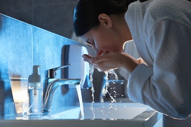 Photo of Woman washing her face over sink in bathroom