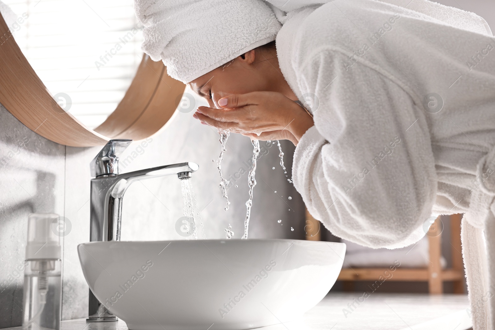 Photo of Woman washing her face over sink in bathroom