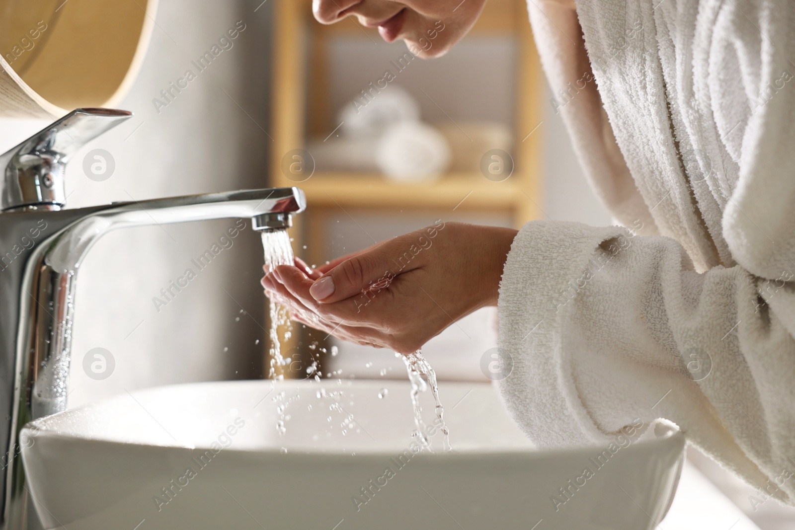 Photo of Woman washing her face over sink in bathroom, closeup