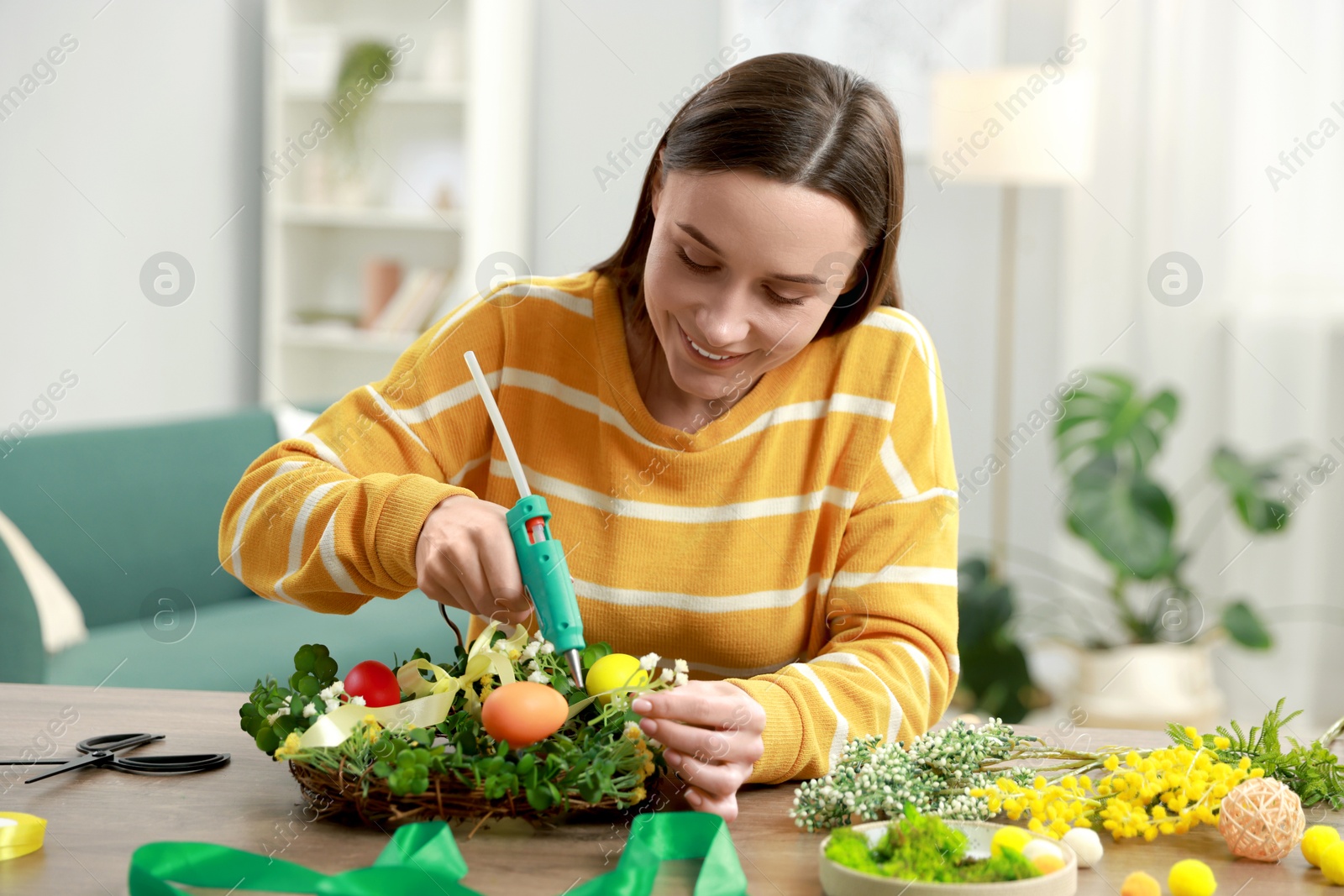 Photo of Woman with hot glue gun making craft at table indoors