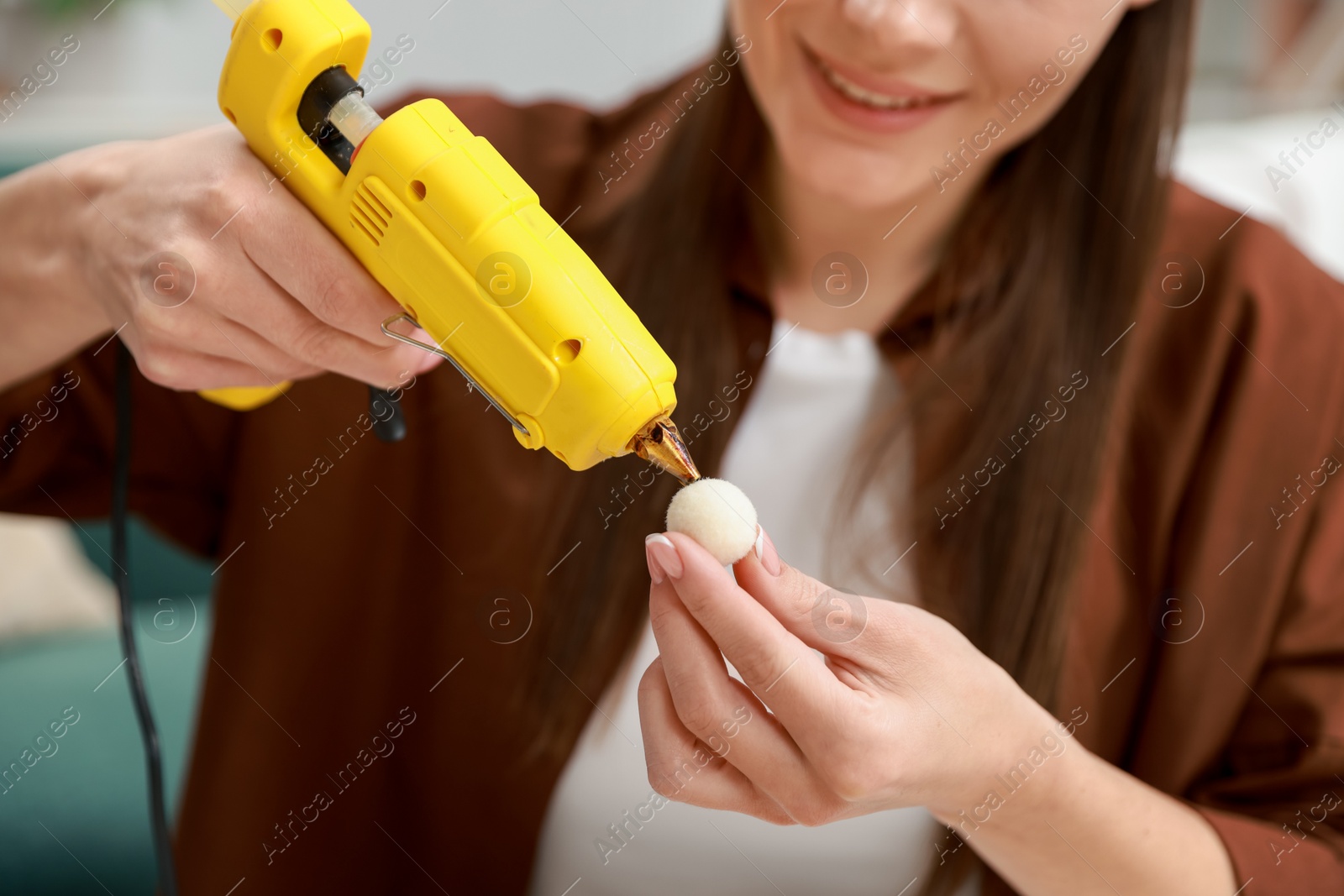 Photo of Woman with hot glue gun making craft indoors, closeup