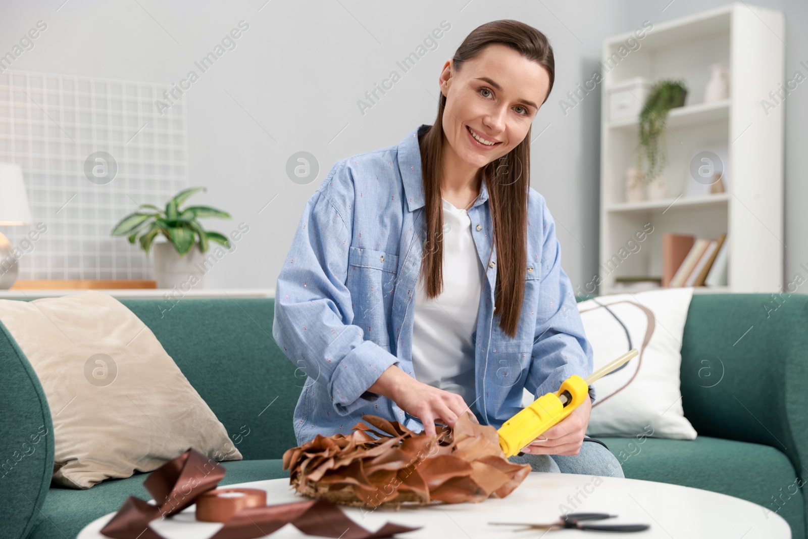 Photo of Woman with hot glue gun making craft at table indoors