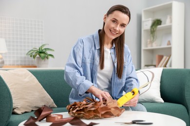 Photo of Woman with hot glue gun making craft at table indoors