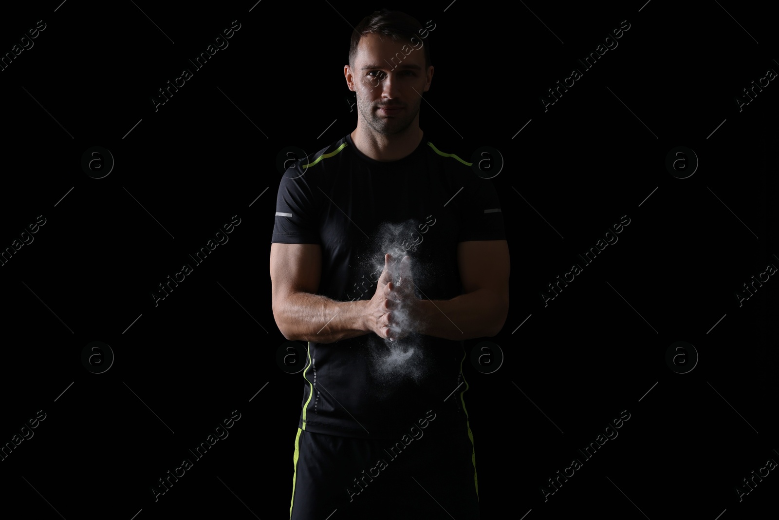 Photo of Man clapping hands with talcum powder before training on black background