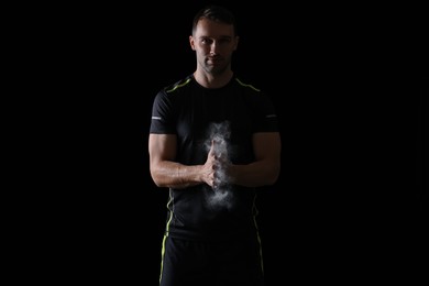 Photo of Man clapping hands with talcum powder before training on black background