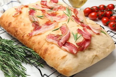 Photo of Delicious focaccia bread with bacon and rosemary on white table, closeup