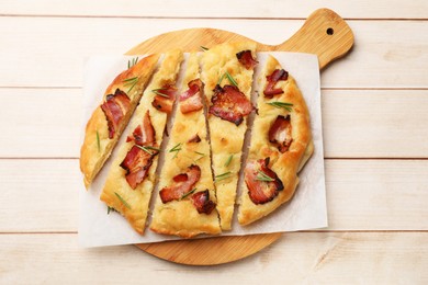 Photo of Slices of delicious focaccia bread with bacon and rosemary on wooden table, top view