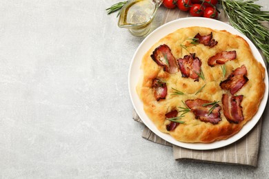 Photo of Delicious focaccia bread with bacon, rosemary, tomatoes and oil on light grey table, flat lay. Space for text