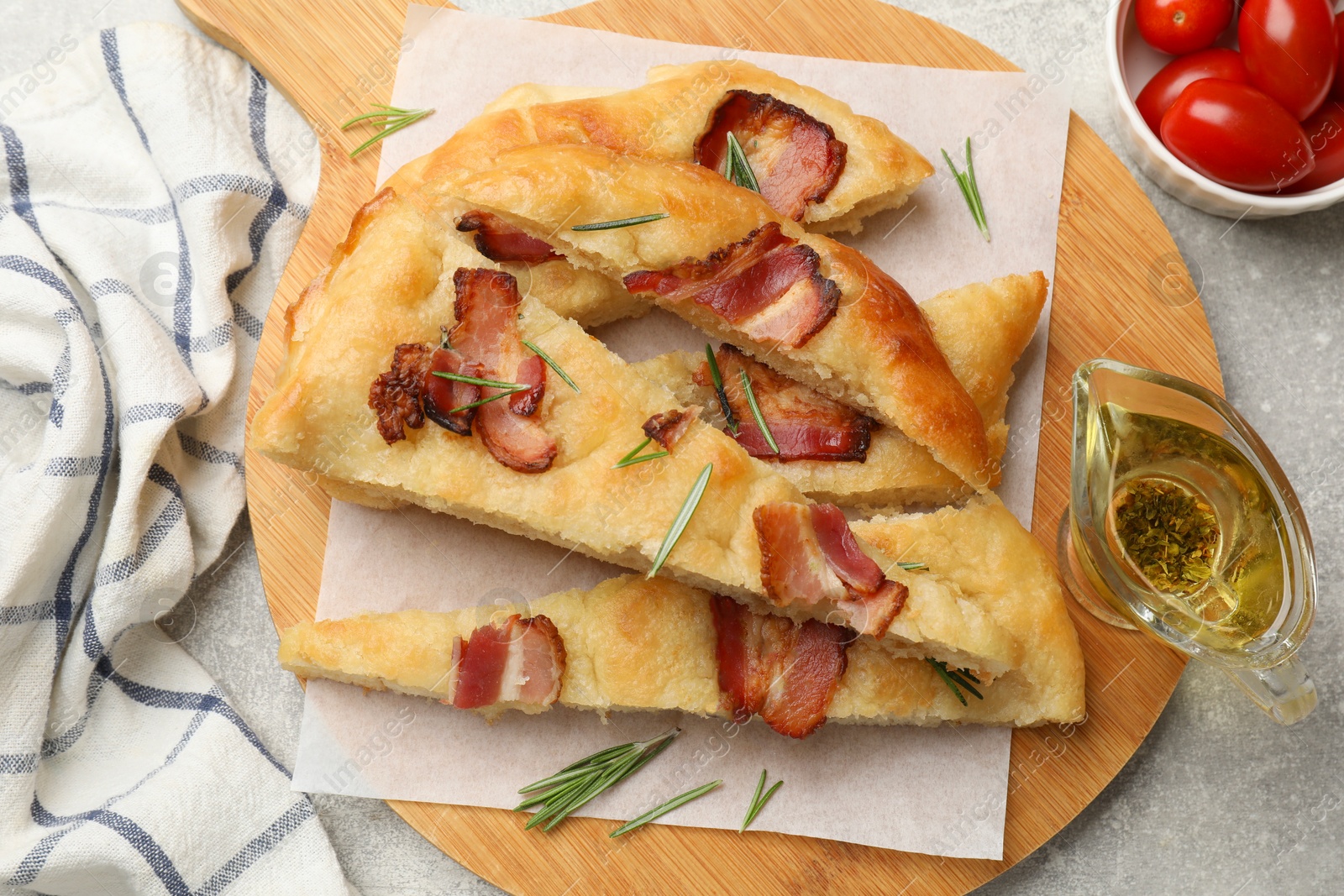 Photo of Pieces of delicious focaccia bread with bacon served on grey table, flat lay