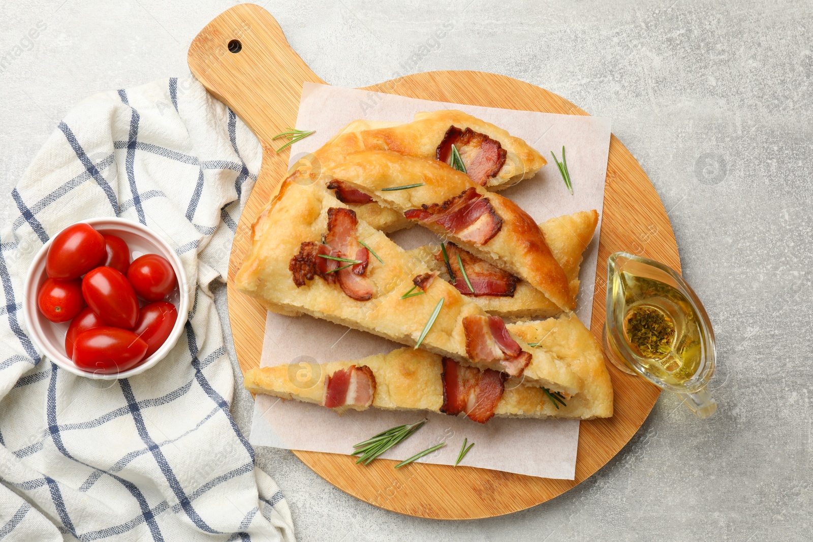 Photo of Pieces of delicious focaccia bread with bacon served on grey table, flat lay