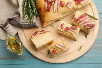 Photo of Pieces of delicious focaccia bread with bacon served on blue wooden table, flat lay