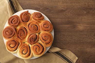 Photo of Freshly baked cinnamon rolls on wooden table, top view. Space for text