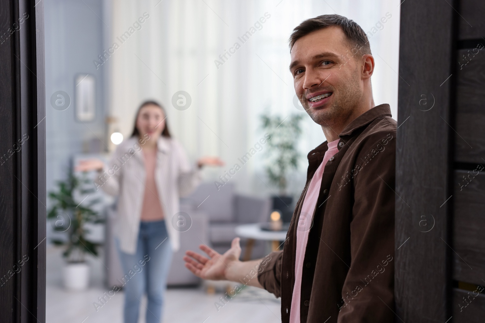 Photo of Lovely couple welcoming guests to their apartment, selective focus