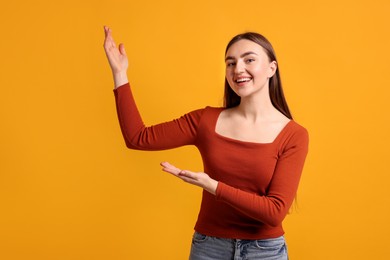 Happy woman welcoming guests on orange background