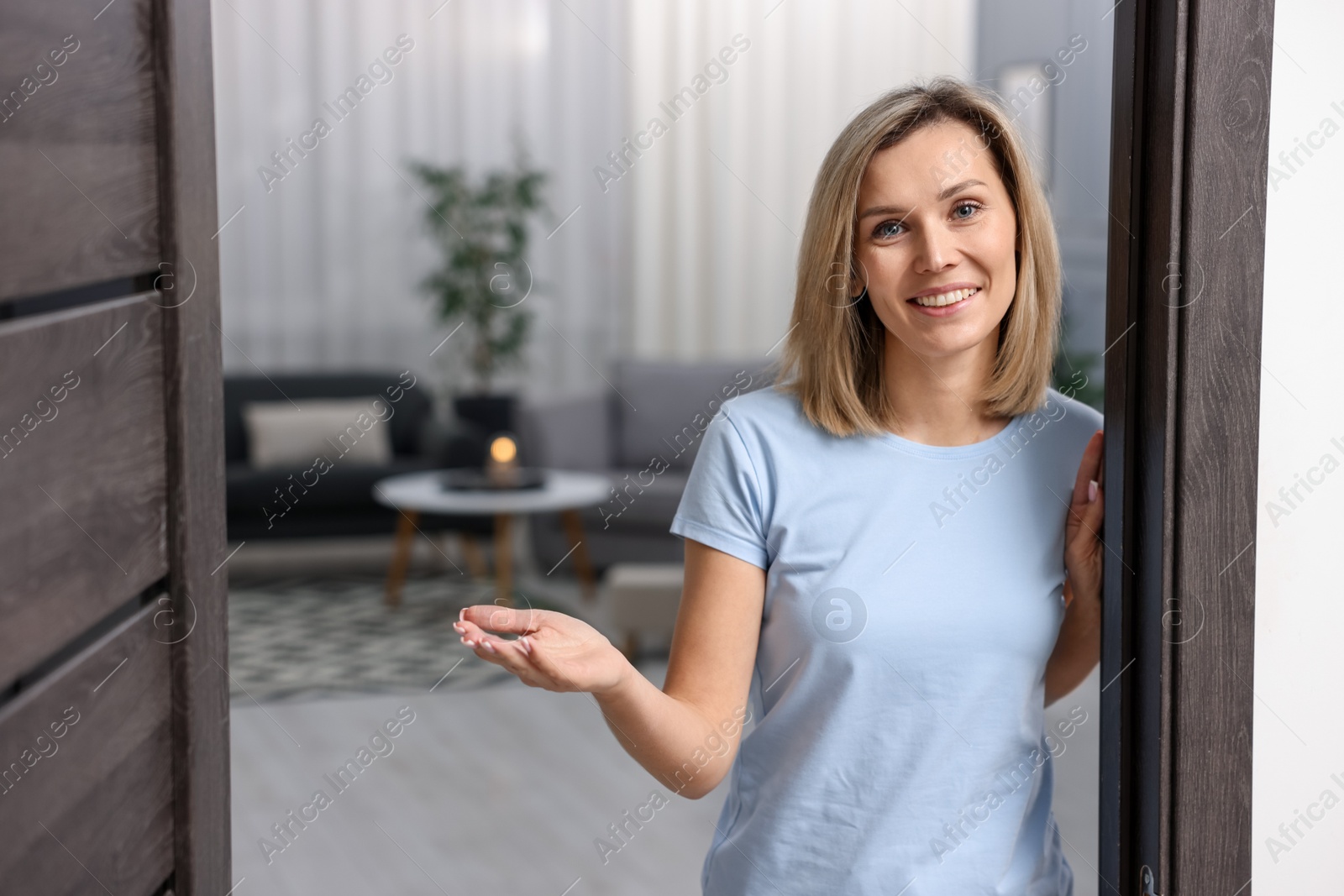 Photo of Happy woman welcoming guests to her house