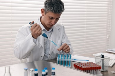 Photo of Scientist with micropipette and test tubes working in laboratory