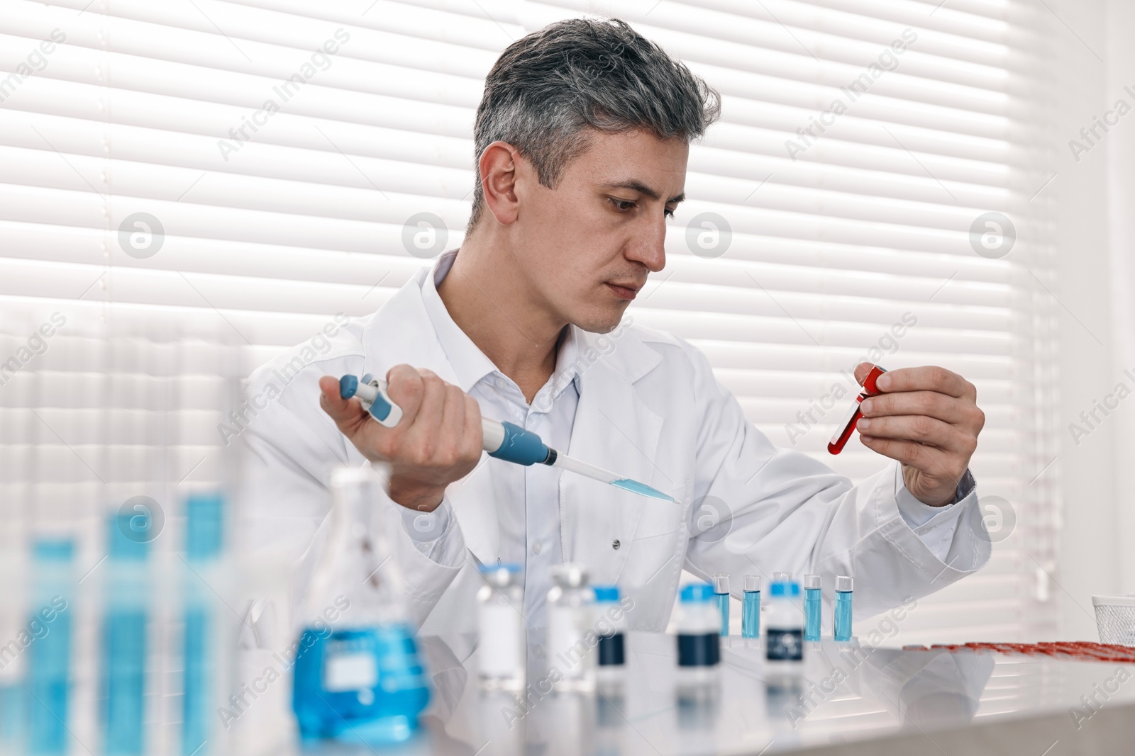 Photo of Scientist with micropipette and test tubes working in laboratory