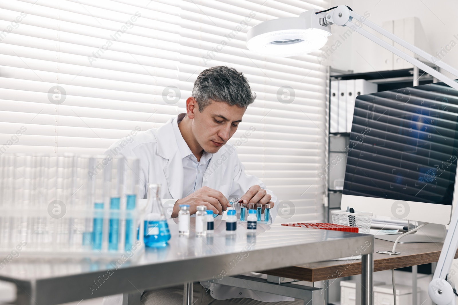 Photo of Scientist with test tubes working in laboratory