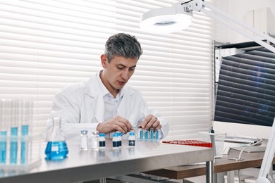 Photo of Scientist with test tubes working in laboratory