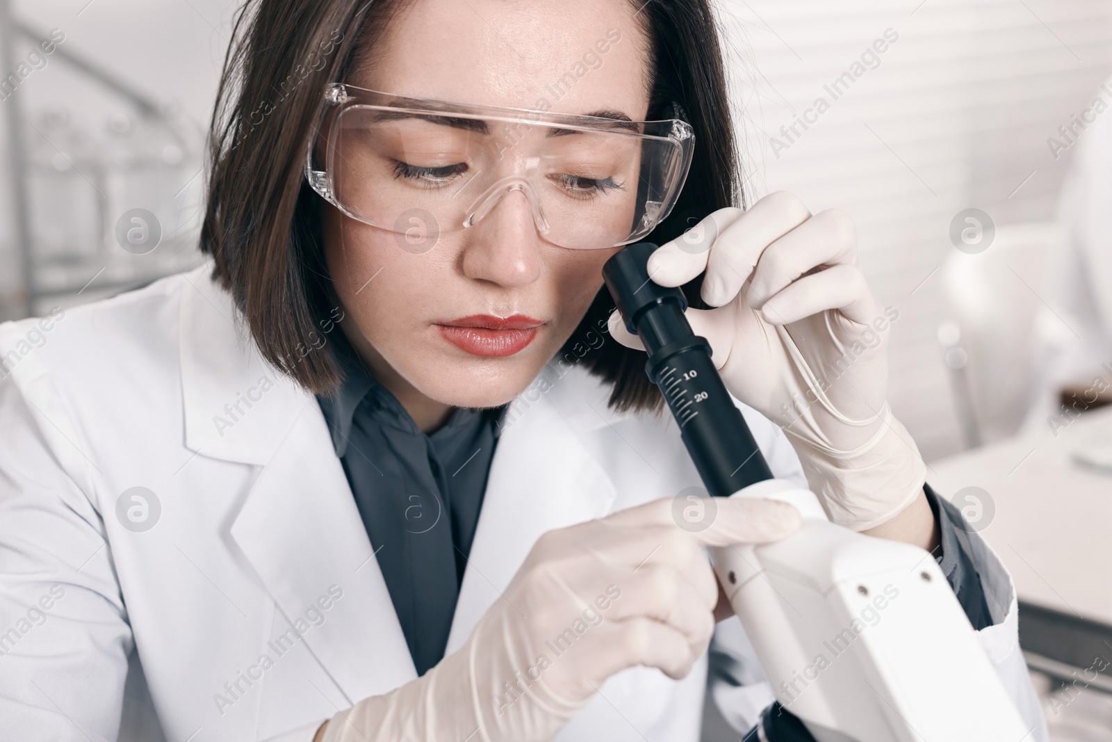 Photo of Scientist working with microscope in laboratory, closeup