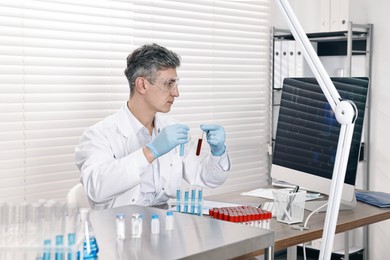 Photo of Scientist with test tubes working at table in laboratory