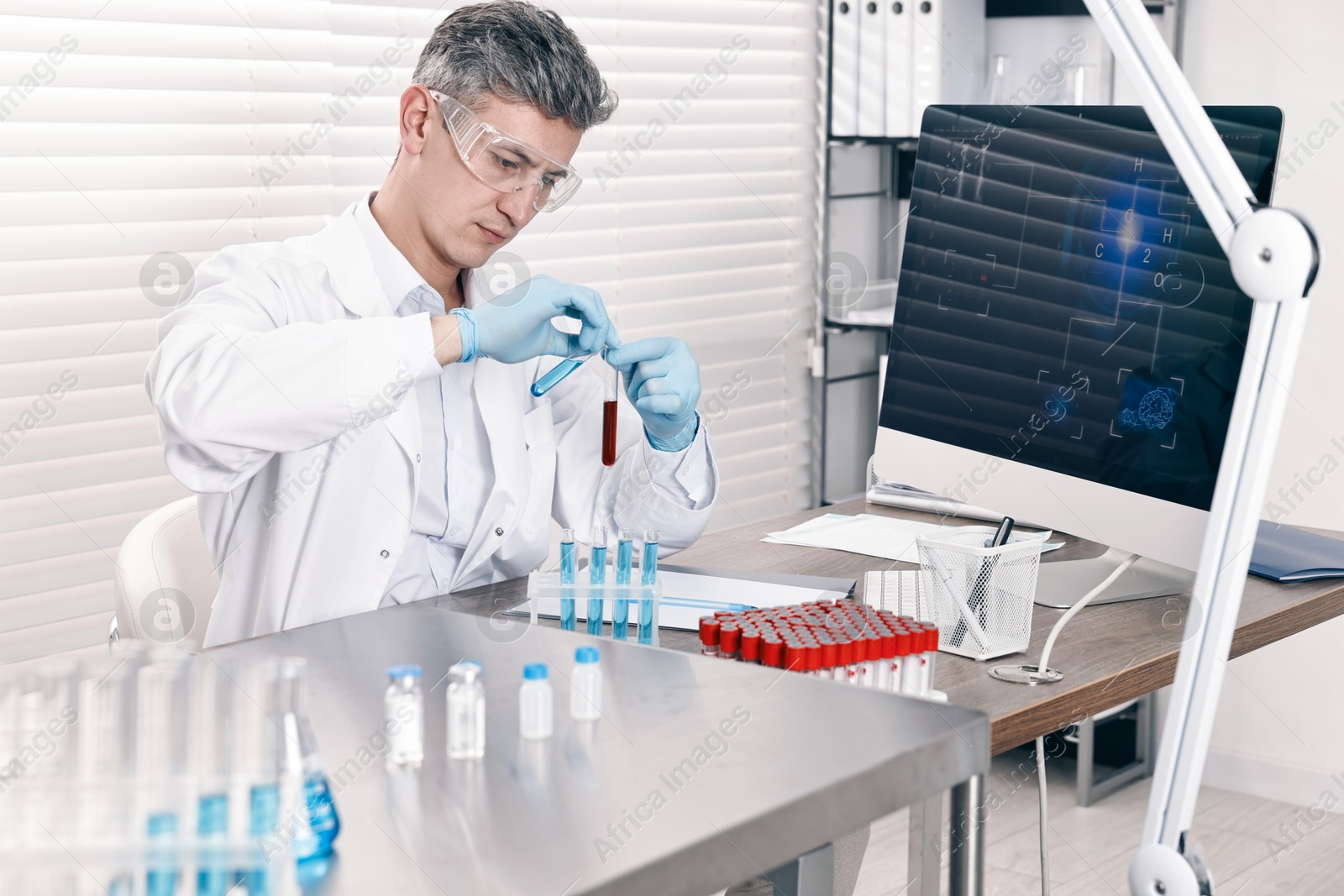 Photo of Scientist with test tubes working at table in laboratory