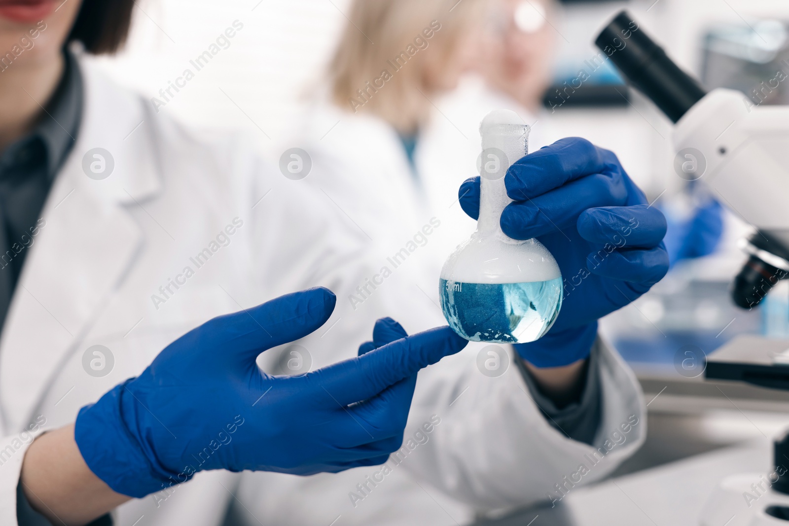 Photo of Scientist with flask working at table in laboratory, closeup