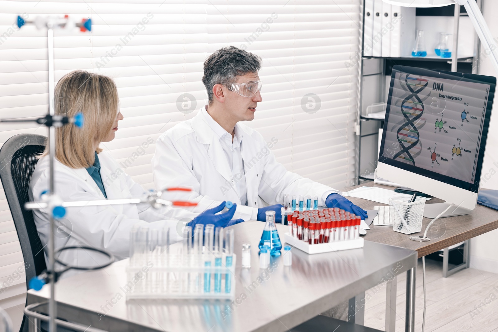 Photo of Scientists working with computer and samples at table in laboratory