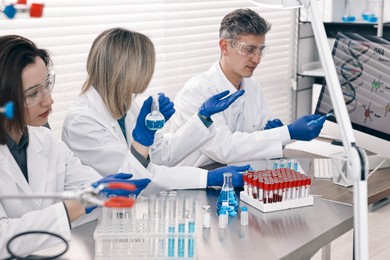 Photo of Scientists working with computer and samples at table in laboratory