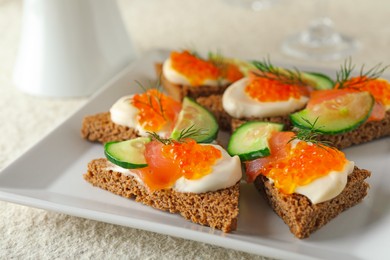 Photo of Tasty canapes with salmon and cucumber on white table, closeup