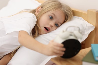 Photo of Overslept girl with alarm clock in bed at home