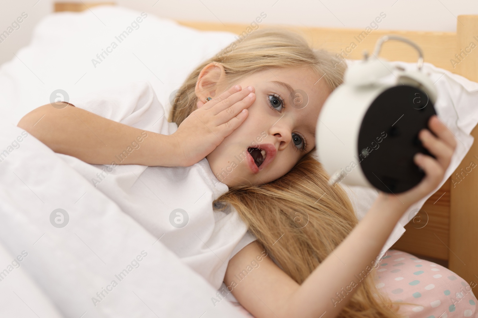 Photo of Overslept girl with alarm clock in bed at home