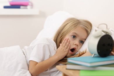 Photo of Overslept girl with alarm clock in bed at home