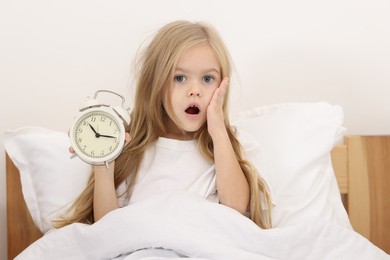 Photo of Overslept girl with alarm clock in bed at home