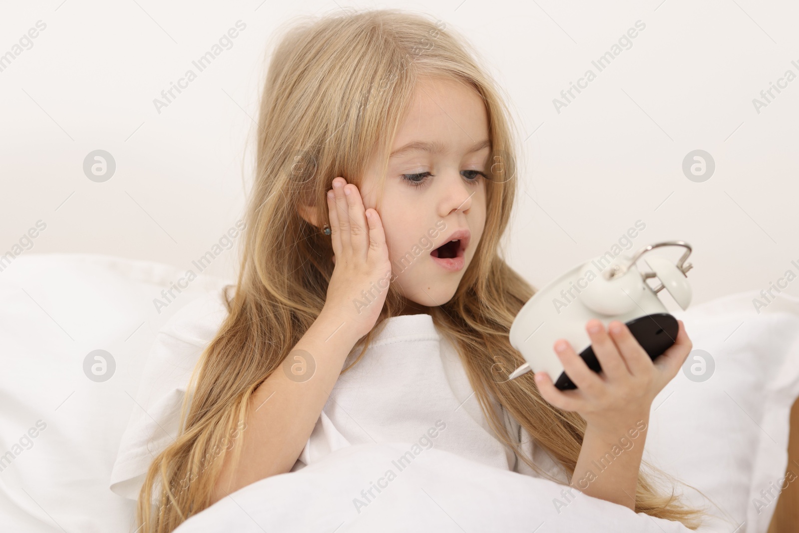 Photo of Overslept girl with alarm clock in bed at home