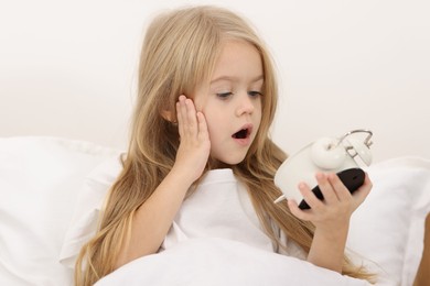 Photo of Overslept girl with alarm clock in bed at home