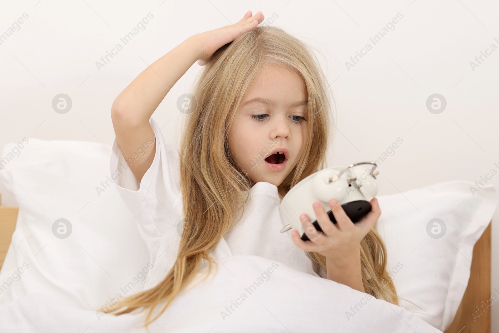 Photo of Overslept girl with alarm clock in bed at home