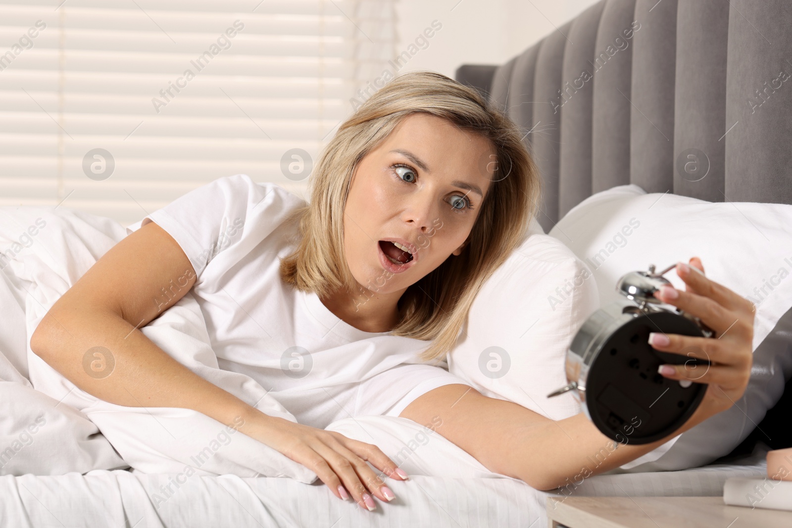 Photo of Overslept woman with alarm clock in bed at home