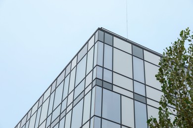 Photo of Modern building with many windows against blue sky, low angle view