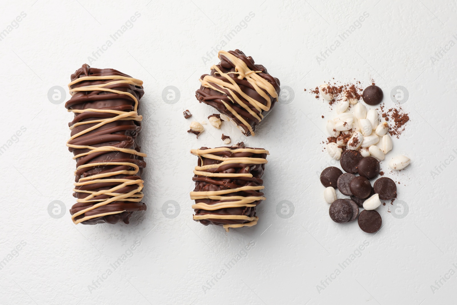 Photo of Delicious chocolate puffed rice bars and cacao chips on white table, flat lay