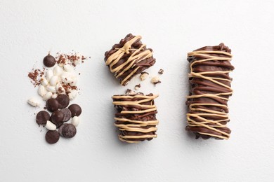 Photo of Delicious chocolate puffed rice bars and cacao chips on white table, flat lay