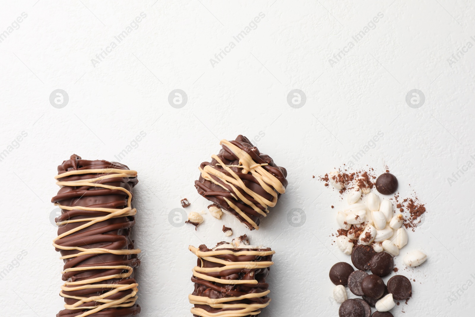 Photo of Delicious chocolate puffed rice bars and cacao chips on white table, flat lay