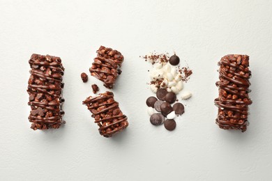 Delicious chocolate puffed rice bars and cacao chips on white table, flat lay