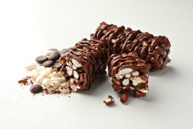 Photo of Delicious chocolate puffed rice bars and cacao chips on white table, closeup