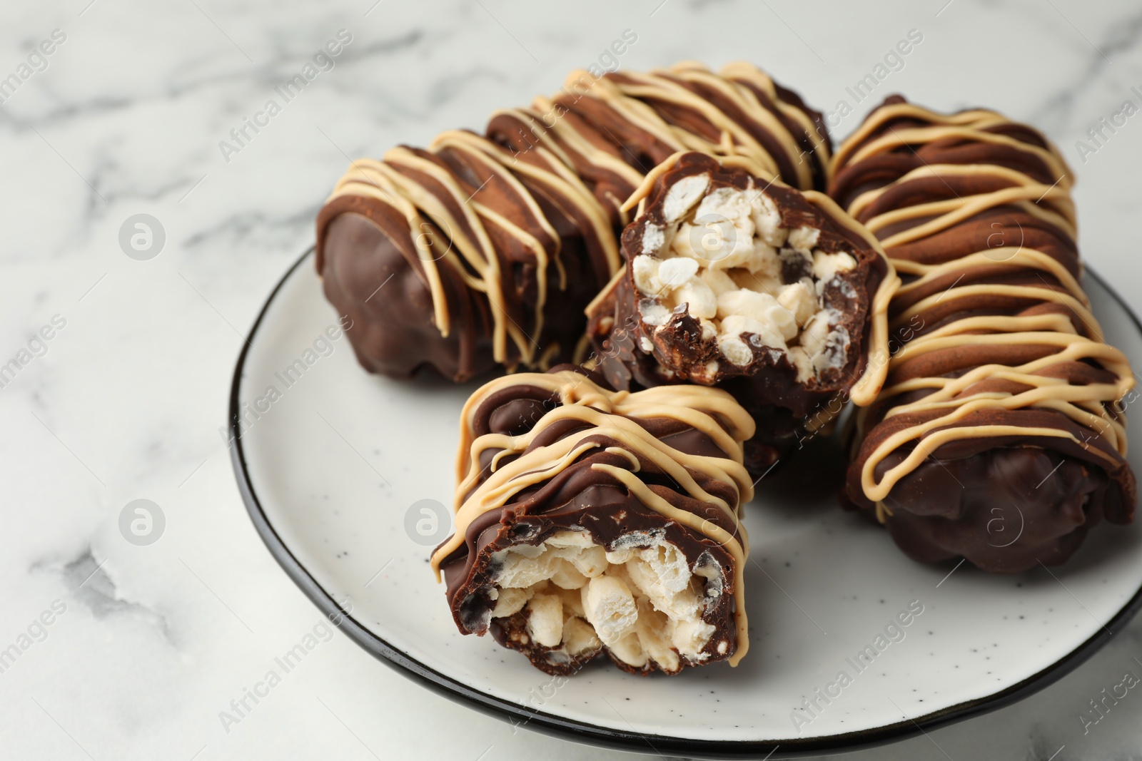 Photo of Delicious chocolate puffed rice bars on white marble table, closeup