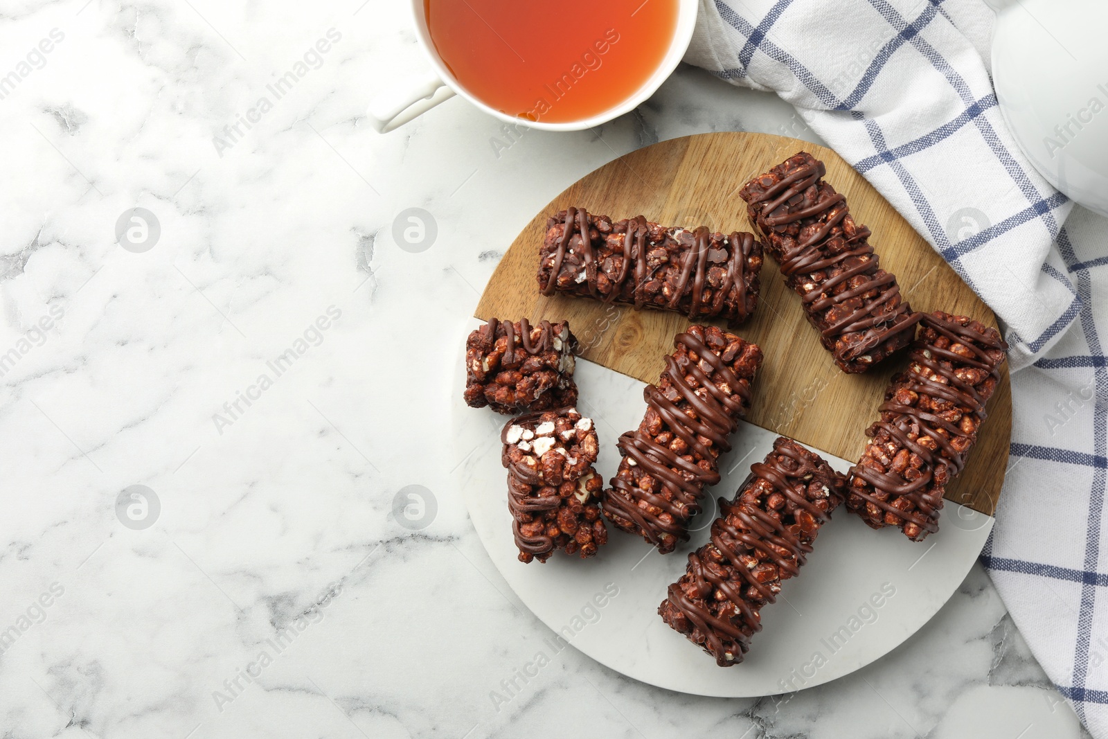 Photo of Delicious chocolate puffed rice bars on white marble table, top view. Space for text