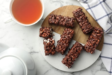 Delicious chocolate puffed rice bars on white marble table, top view