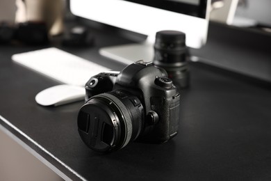 Photo of Professional camera and computer on black desk indoors, selective focus