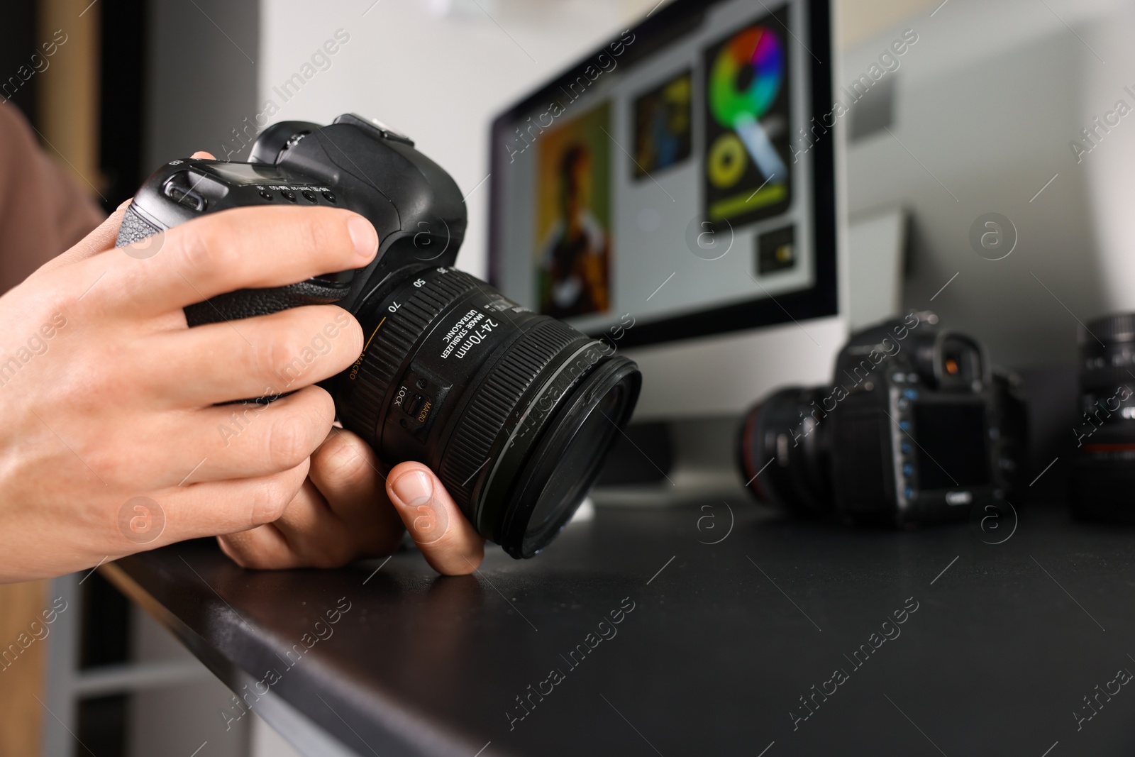 Photo of Photographer with professional camera at black desk indoors, closeup